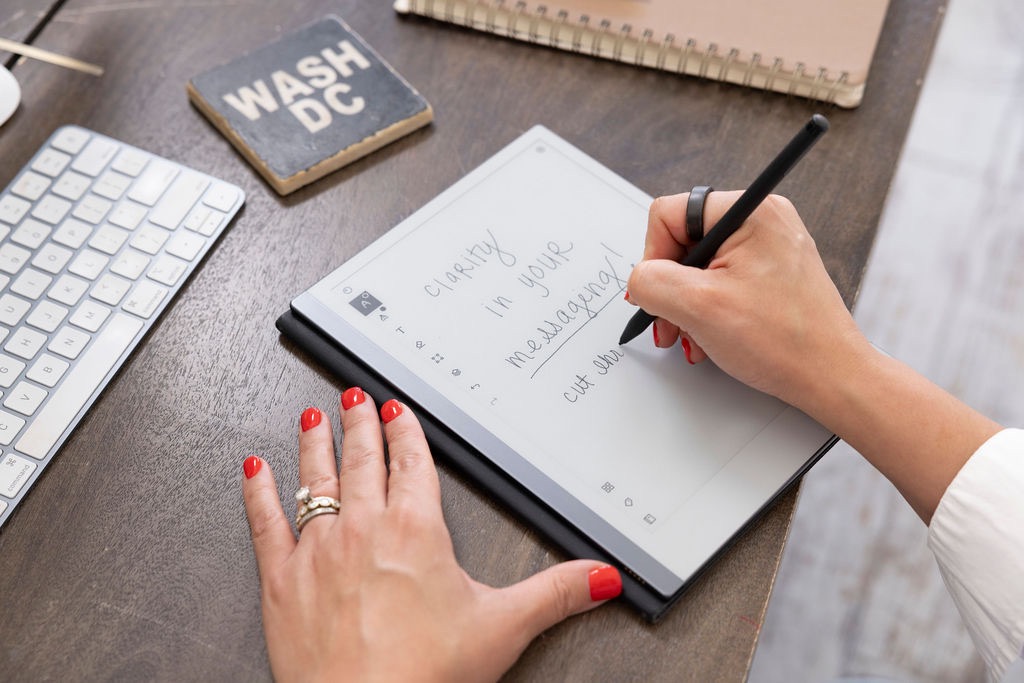 Hands writing 'Clarity in your messaging' in a notebook